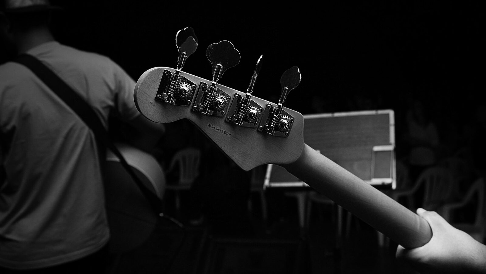 grayscale photography of person carrying guitar