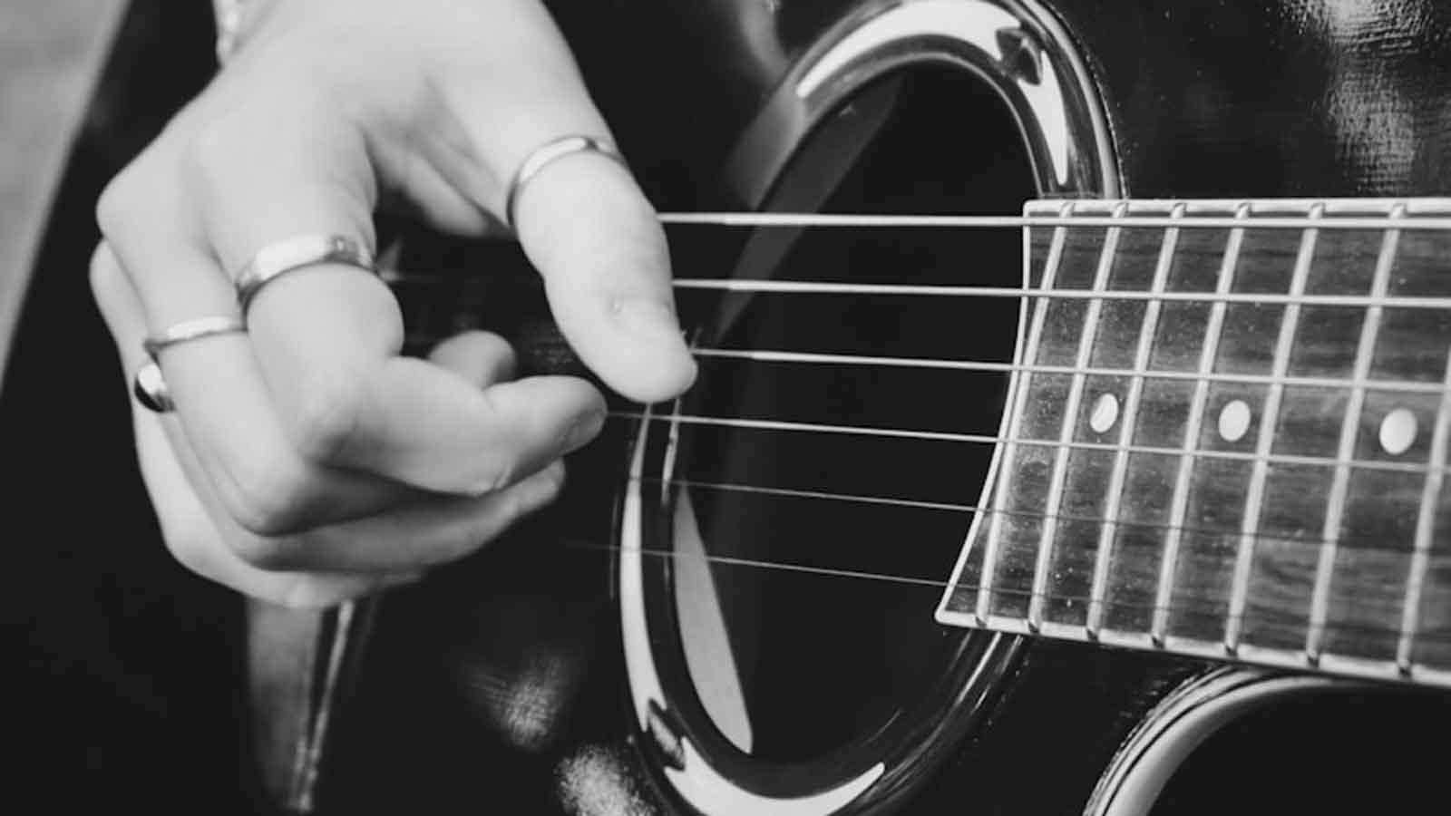 person playing guitar in grayscale photography