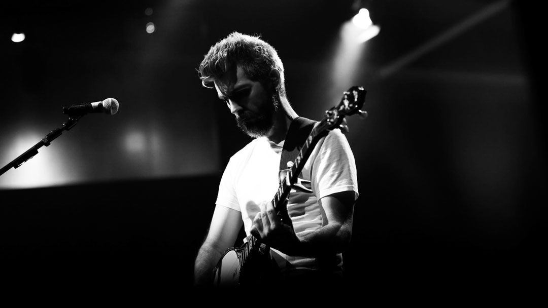 grayscale photography of person carrying guitar